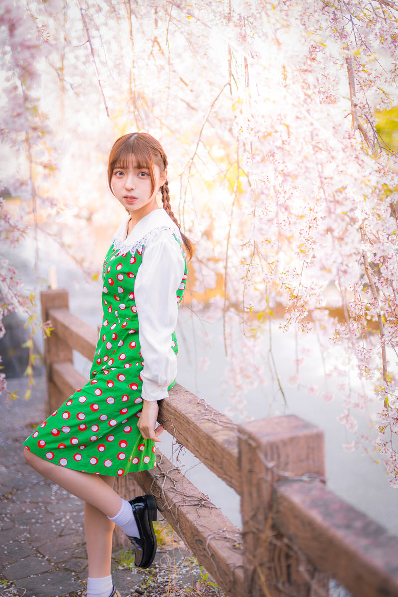 満開のしだれ桜の下で緑のワンピースを着て立つ女性［モデル：高尾実生］