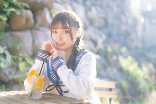 カフェでくつろぐ制服姿の女子高生がドリンクを片手に笑顔