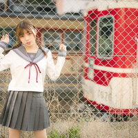 停車する有馬線を背景にした女子高生のポートレートの写真
