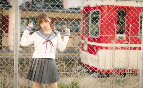 停車する有馬線を背景にした女子高生のポートレート