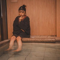 足湯に浸りながら考えごとをする女性の写真