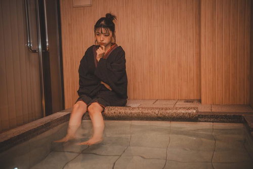 足湯に浸りながら考えごとをする女性