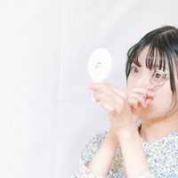 眼鏡をかけた女性がビューラーでまつ毛をカールする横顔の写真