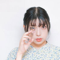 ビューラーでまつ毛をカールする女性のナチュラルメイクの写真