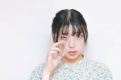 ビューラーでまつ毛をカールする女性のナチュラルメイク