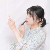 鏡を見ながら口紅を塗るビューティーテクニックの写真