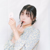 手鏡を見ながら口紅を塗り直す女性のメイク直しの写真