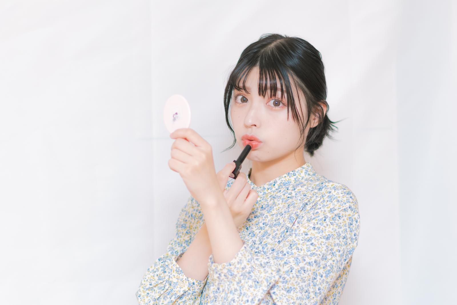 鏡を見ながら口紅を塗る女性のメイクシーン［モデル：高尾実生］