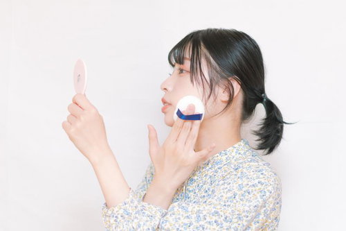 パフで完璧なコンプレクションを作る女性の横顔