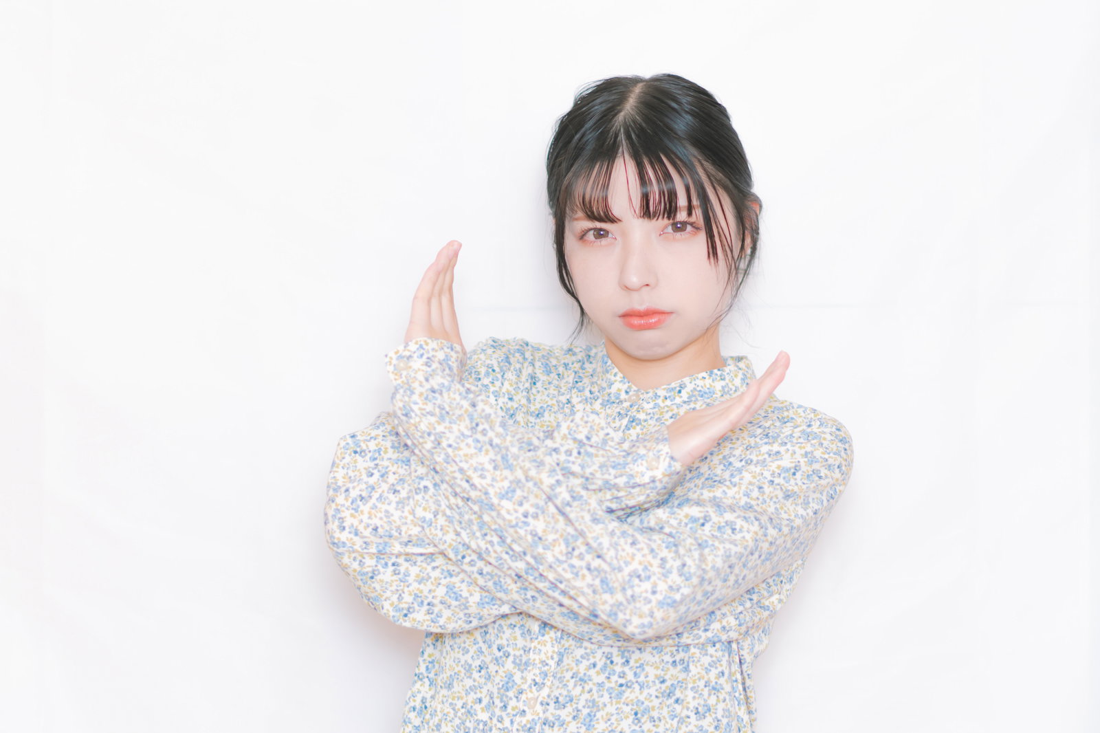 両手を交差させてNGジェスチャーをする女性［モデル：高尾実生］