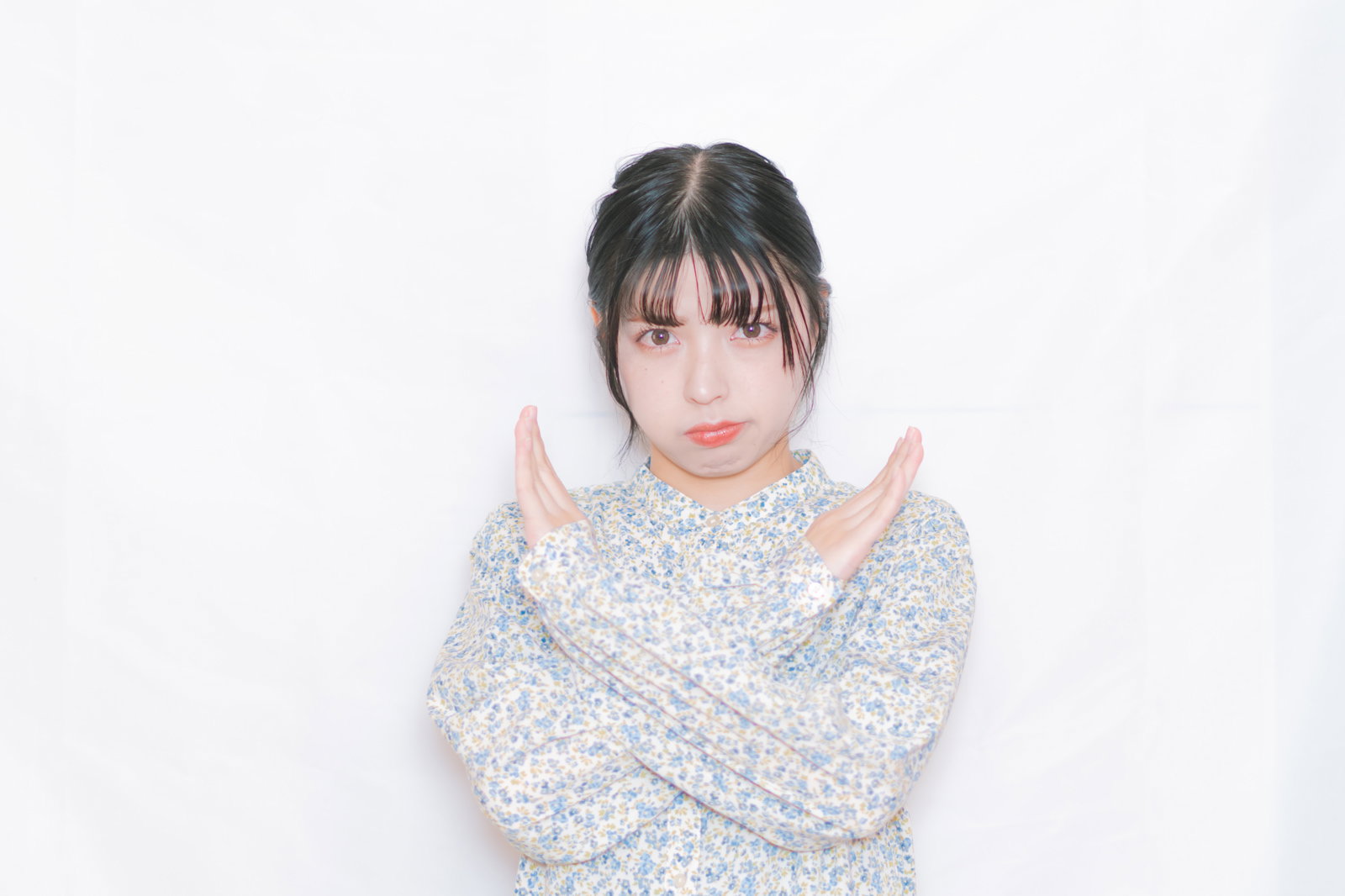 両腕を上げてNGのジェスチャーをする女性［モデル：高尾実生］