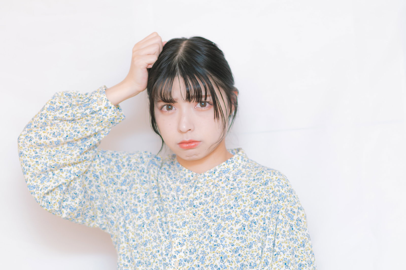 頭痛で悩む表情の女性が片手を頭に当てている［モデル：高尾実生］