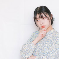 首を傾げて俯瞰して考える青い花柄シャツの女性の写真