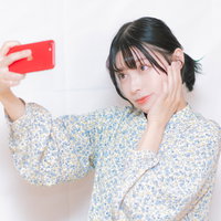 赤いスマートフォンで自撮りする女性の歯痛表情の写真