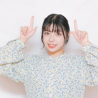 両手でピースサインをする花柄シャツの女性の写真
