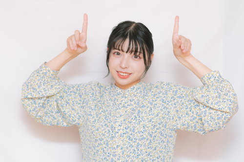 上部を指差して笑顔の若い女性のポートレート