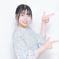 両手で左方向を指差す笑顔の女性、案内ポーズの写真