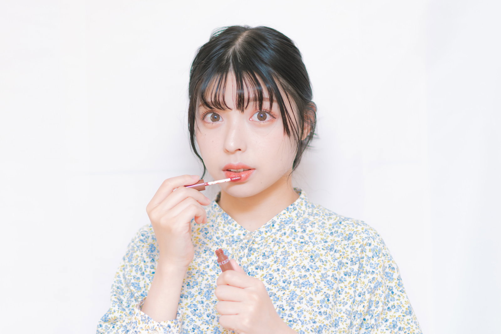 ティントリップを唇に塗る女性［モデル：高尾実生］