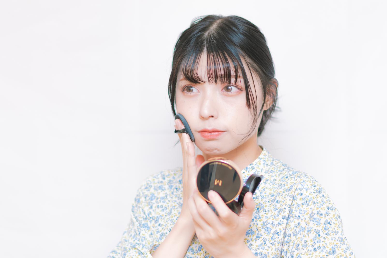 ワイヤレスイヤホンを着けながらコンパクトミラーでリップメイクを直す女性［モデル：高尾実生］