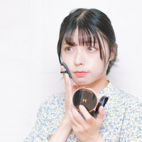 ワイヤレスイヤホンを装着して化粧直しをする女性の写真