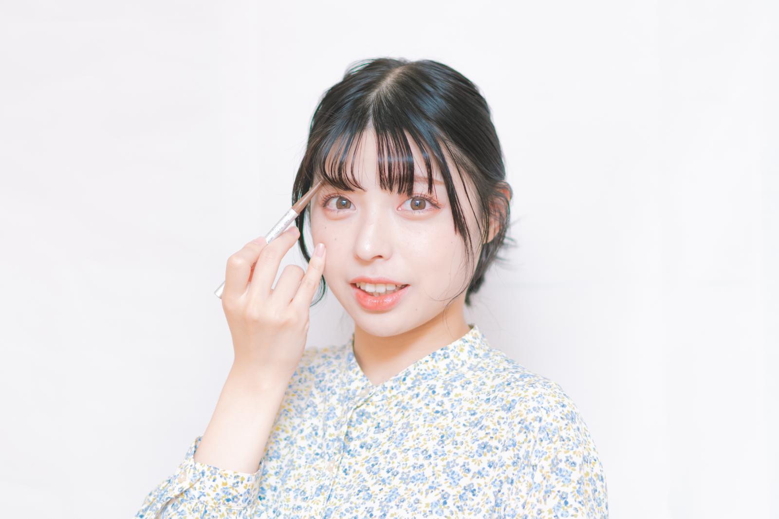 眉ペンで眉毛を描く、笑顔の女性［モデル：高尾実生］