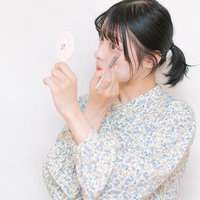 鏡を見ながら眉ブラシで目元を整える化粧テクニックの写真