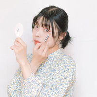 鏡を見ながら目元を仕上げるメイクアップシーンの写真