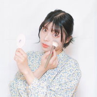 チークブラシでチークを塗って顔を整える女性の写真