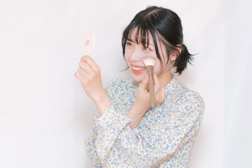 チークブラシで化粧する女性