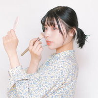 チークブラシでメイクアップを仕上げる女性の横顔の写真