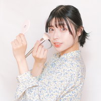 チークブラシを頬に当てる女性のメイクアップの写真