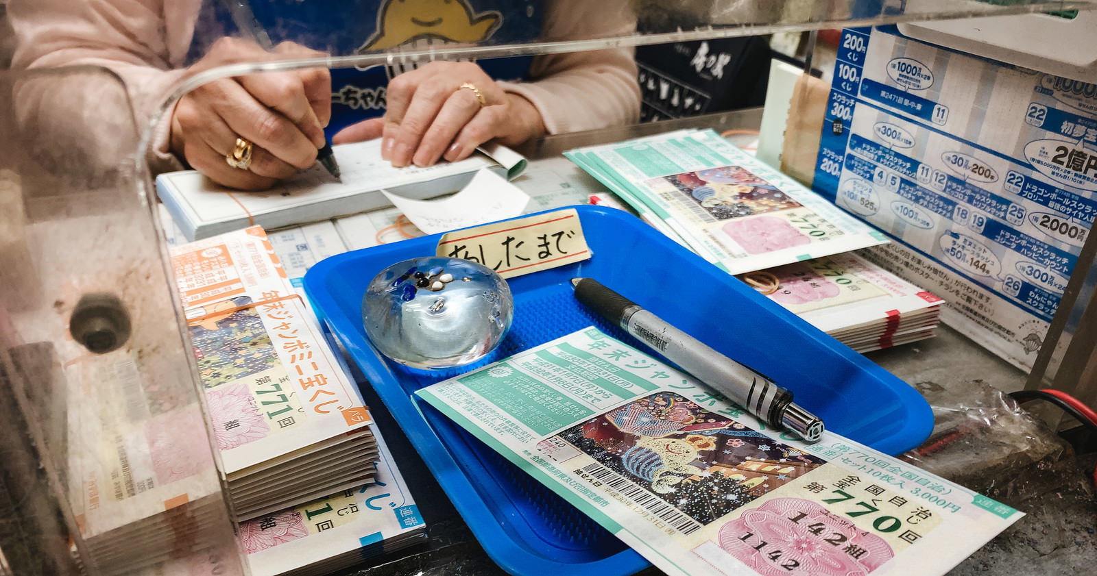 宝くじ売り場で年末ジャンボ宝くじを購入する人の手