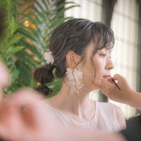 手鏡を見ながらメイク直しをする新婦の化粧直しの写真