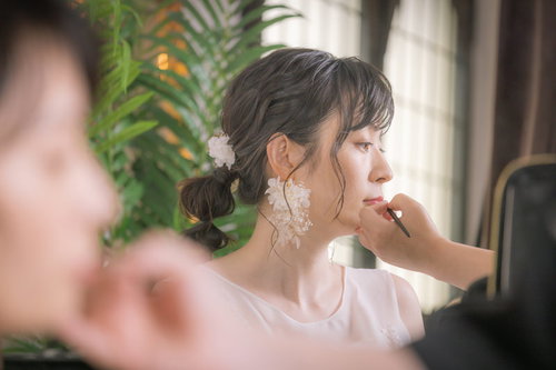 手鏡を見ながらメイク直しをする新婦の化粧直し