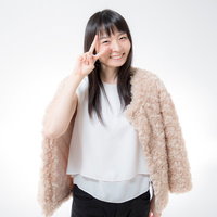 笑顔でピースサインする白トップスの女性のポートレートの写真