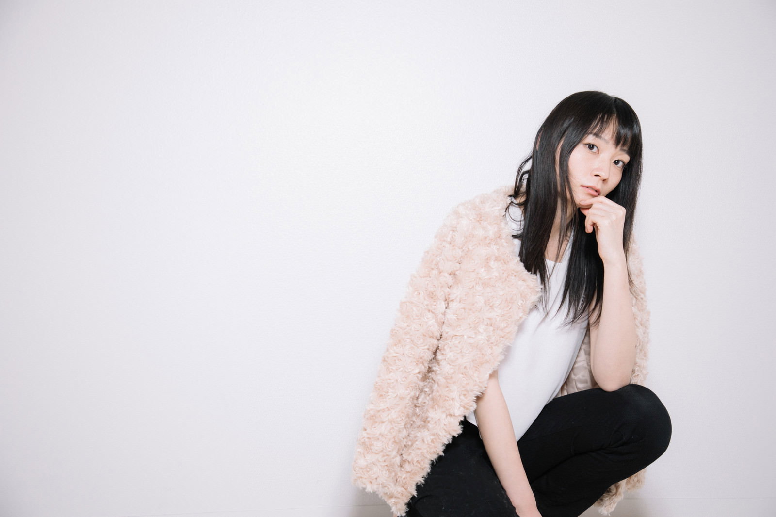 ピンクの羽織物を肩にかけて膝をついている黒髪の女性［モデル：たけべともこ］