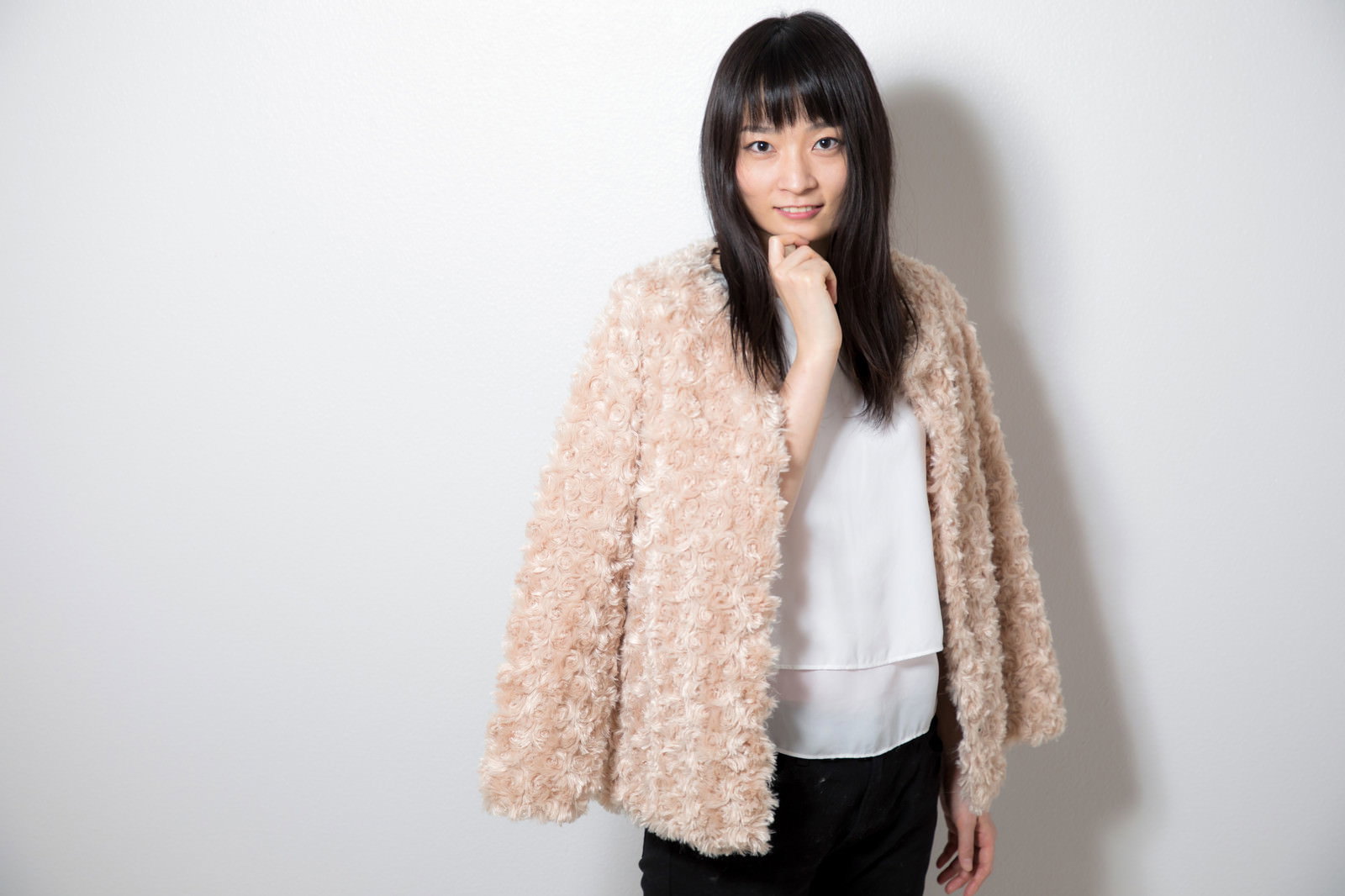 顎に手を添えるポーズで笑顔を見せる女性［モデル：たけべともこ］