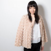 顎に手を添えるあざと女子の笑顔 白い服とベージュ羽織りの室内ショットの写真