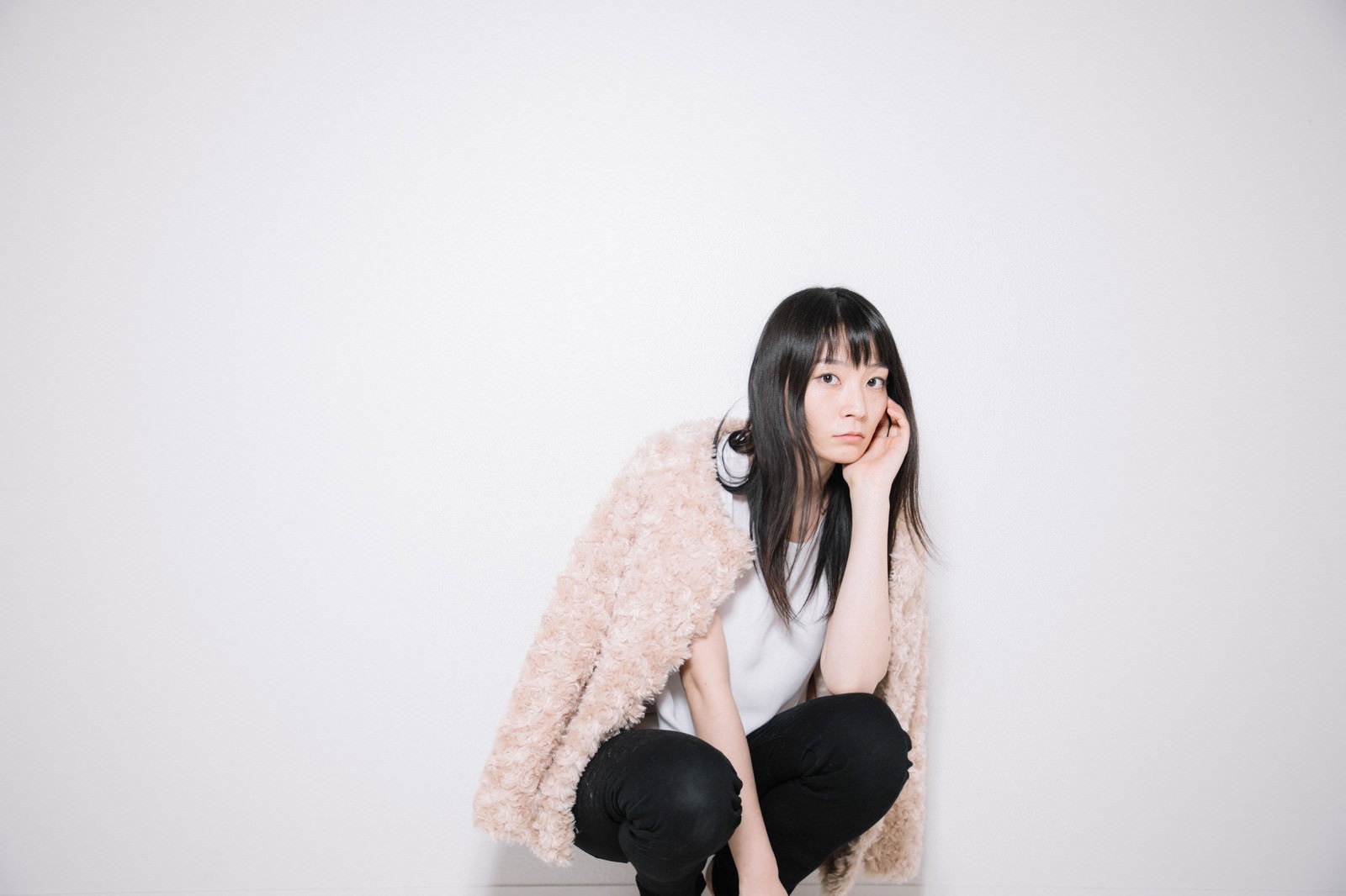 床に座り込んで頬杖をつき考え込んでいる女性［モデル：たけべともこ］