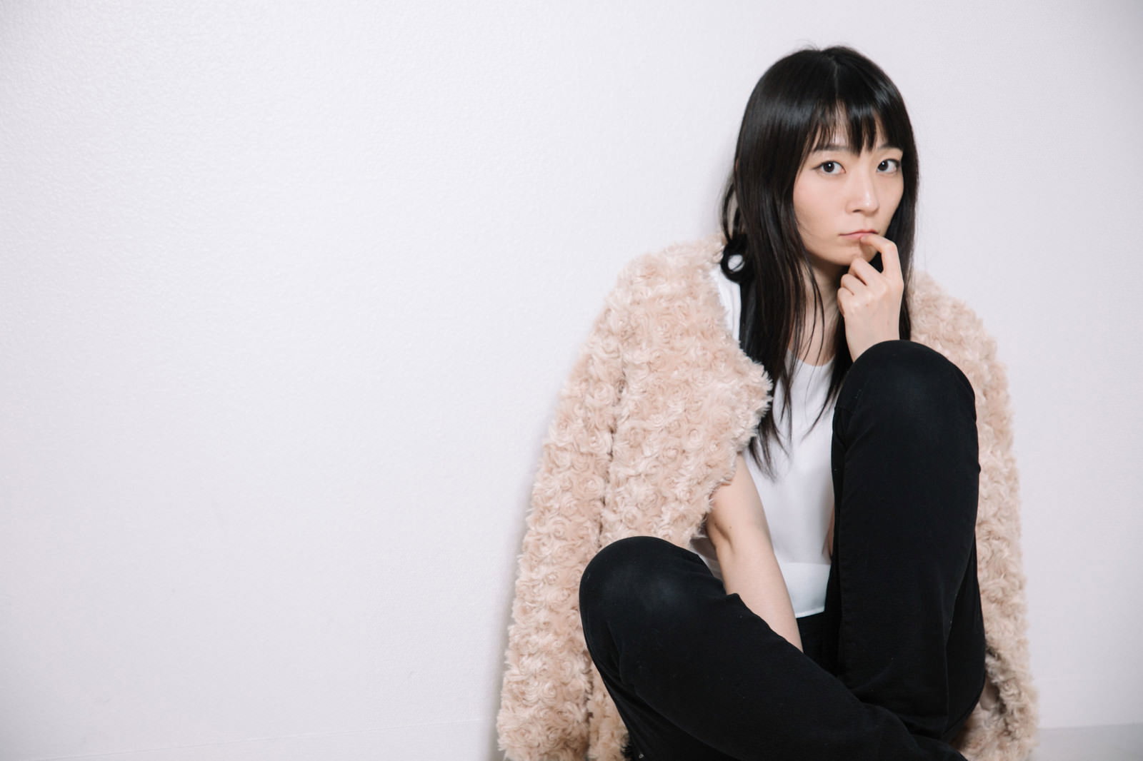 床に座って口元に手を当てる女性［モデル：たけべともこ］