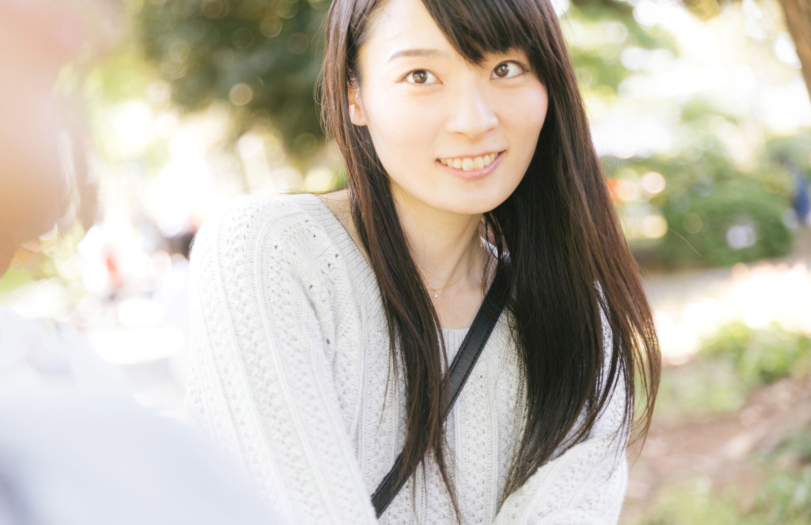 白いトップスを着た女性がスマートフォンで笑顔でセルフィーを撮っている［モデル：たけべともこ］