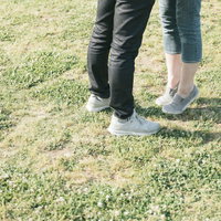 芝生で背伸びする彼女の足元、寄り添うカップルの恋愛シーンの写真