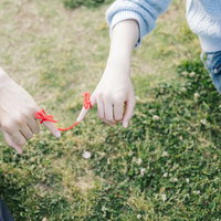 赤い糸でつながった2人、小指に結ぶカップルの手の写真
