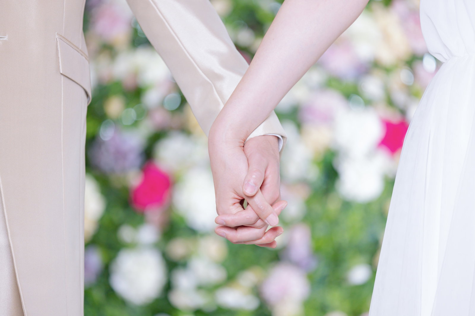結婚式で指を絡めて手を握る新郎新婦［モデル：たけべともこ］