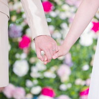 白いドレスの新婦とスーツの新郎が重ねた手と結婚指輪の写真