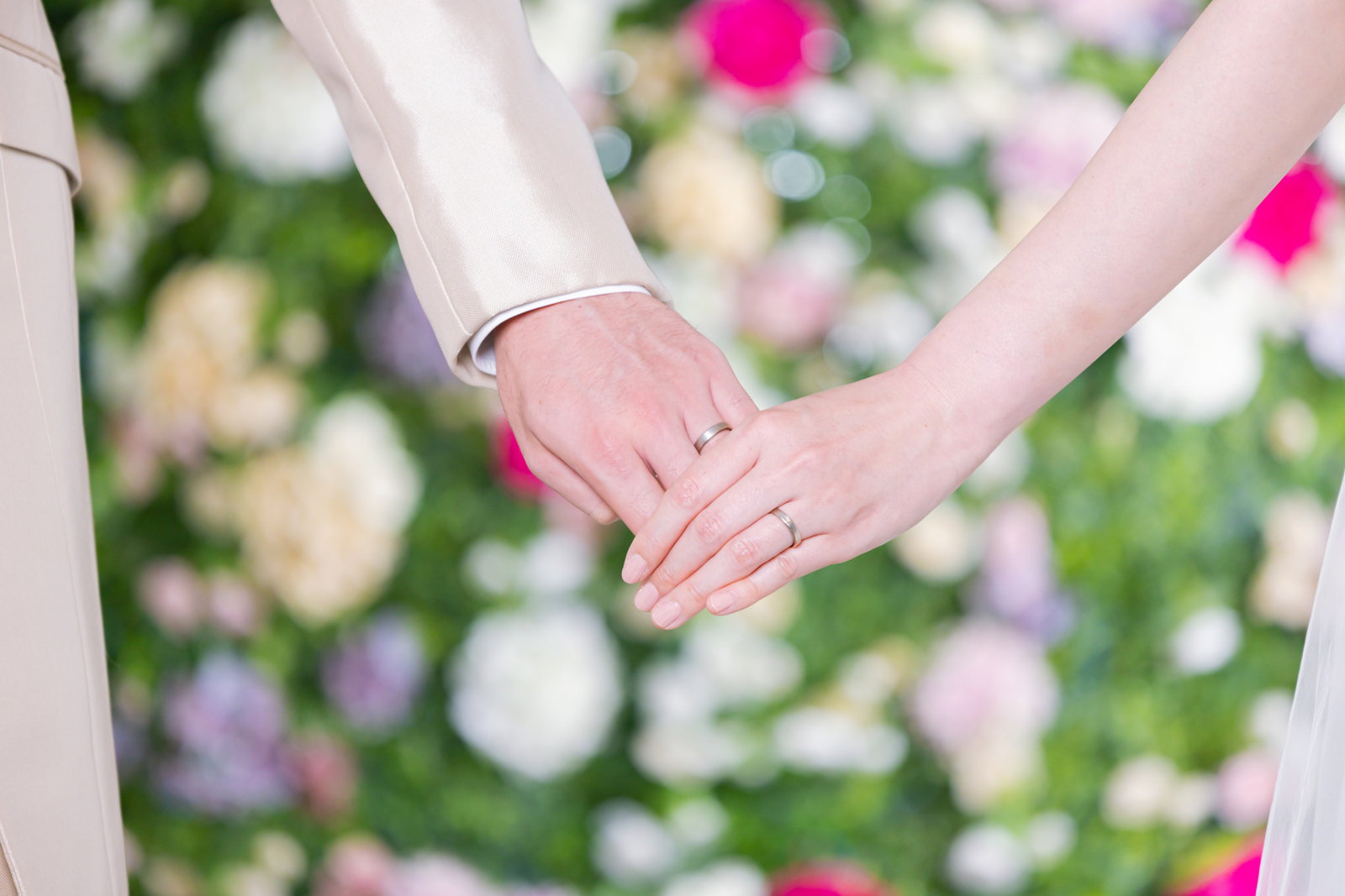 結婚指輪をつけた新郎新婦が手を重ね合わせている様子［モデル：たけべともこ］