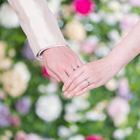 結婚指輪を見えるように手を握り合う新郎新婦の写真