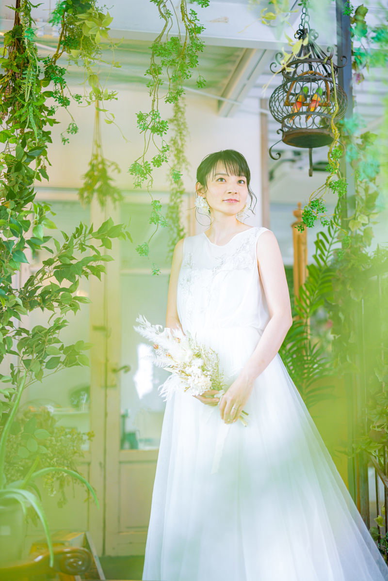 白いウェディングドレスを着て室内で微笑む女性［モデル：たけべともこ］