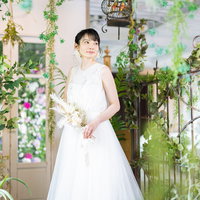 純白のウェディングドレスを着た女性、緑に囲まれた庭園の写真