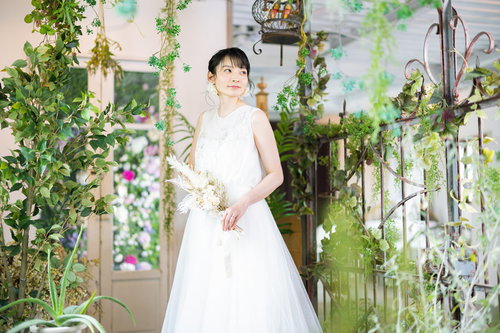 純白のウェディングドレスを着た女性、緑に囲まれた庭園